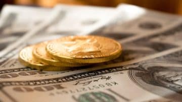 three round gold-colored coins on 100 US dollar banknotes