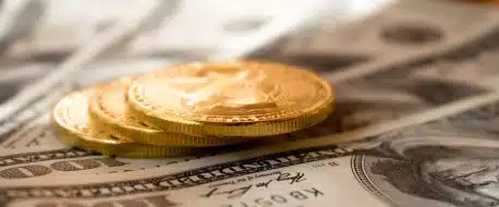three round gold-colored coins on 100 US dollar banknotes
