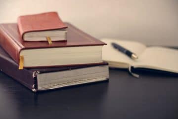 selective focus photography of three books beside opened notebook