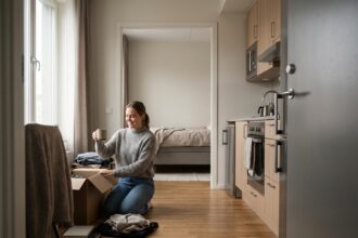 Jeune femme souriante déballant un colis dans un appartement moderne