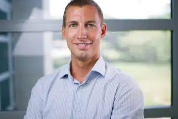 a man in a blue shirt standing in front of a window